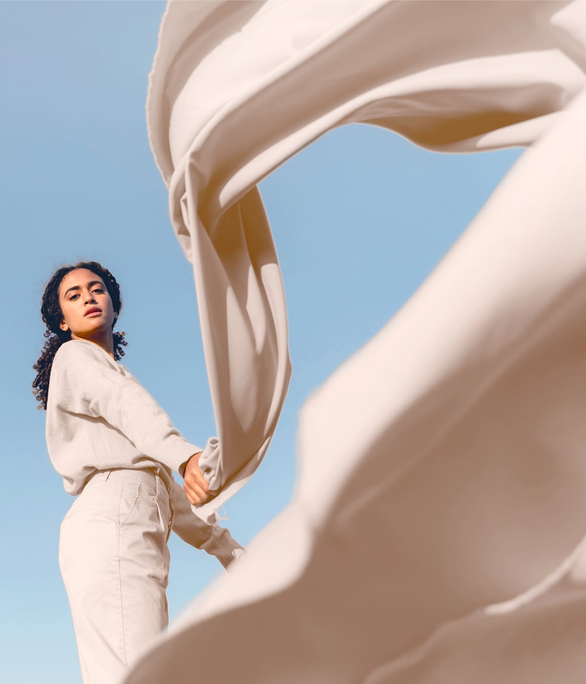 Woman lifting a flowing fabric, expressing responsible fashion. Through Temera’s RFID technology, every material is tracked to support a sustainable journe